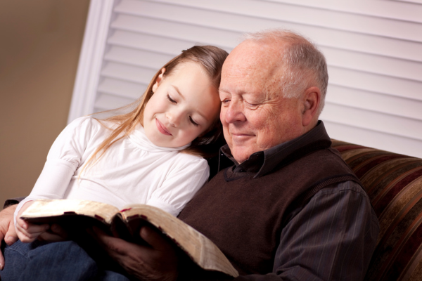 Grandfather reading the Bible to girl